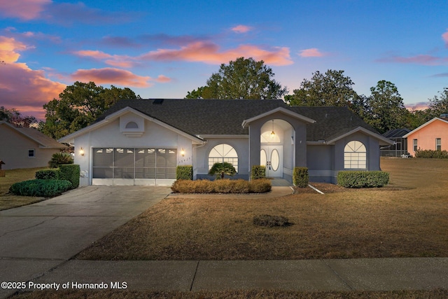 single story home featuring a garage and a lawn