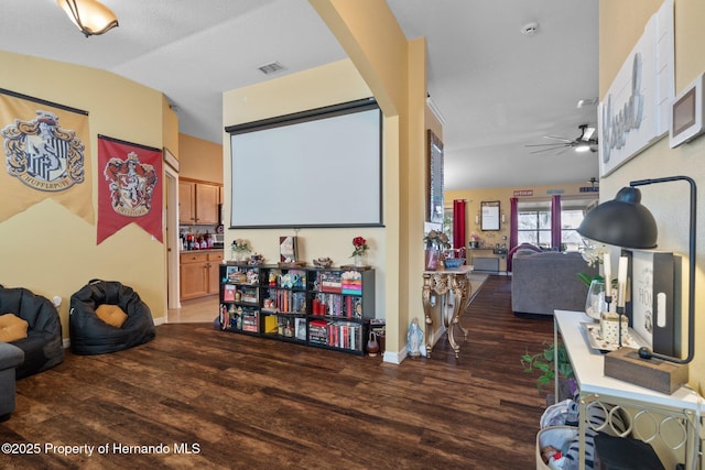 home theater featuring lofted ceiling, dark wood-type flooring, and ceiling fan