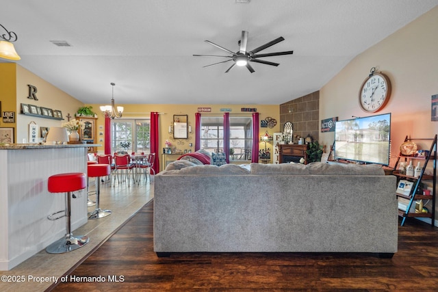 living room featuring dark wood-type flooring, vaulted ceiling, and ceiling fan with notable chandelier