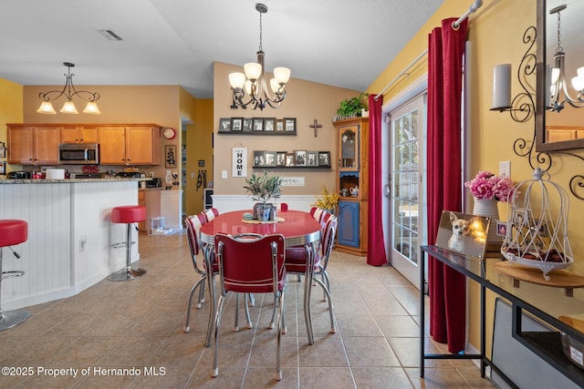 dining area with light tile patterned flooring, lofted ceiling, and a chandelier