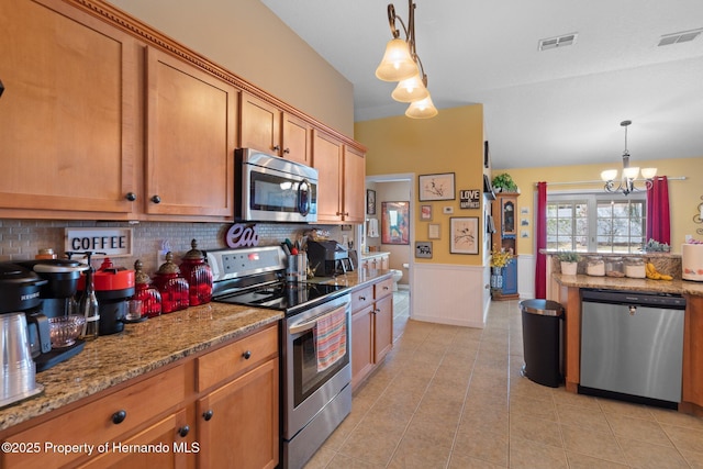 kitchen with light tile patterned flooring, light stone counters, hanging light fixtures, appliances with stainless steel finishes, and a notable chandelier