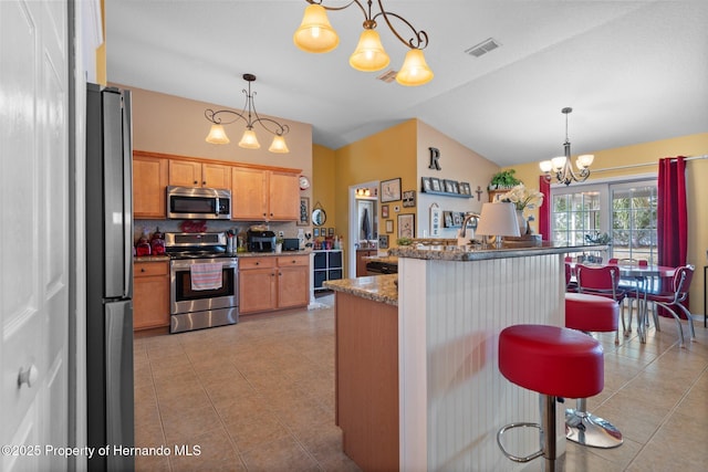 kitchen featuring pendant lighting, appliances with stainless steel finishes, a breakfast bar area, and light tile patterned floors