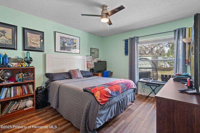 bedroom with ceiling fan, hardwood / wood-style floors, and a textured ceiling