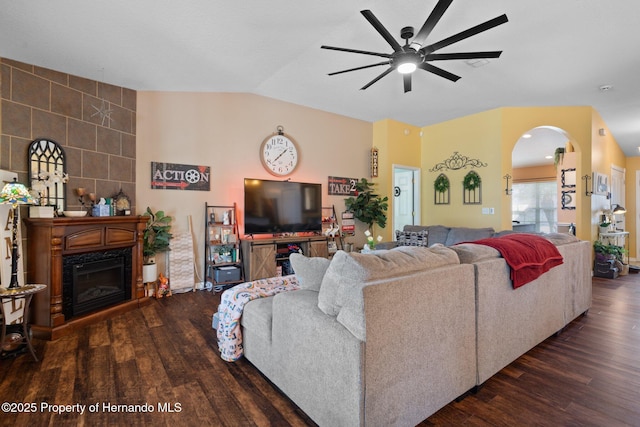 living room featuring lofted ceiling, a fireplace, dark hardwood / wood-style floors, and ceiling fan