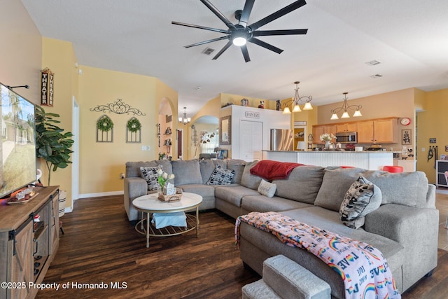 living room with ceiling fan with notable chandelier and dark hardwood / wood-style flooring