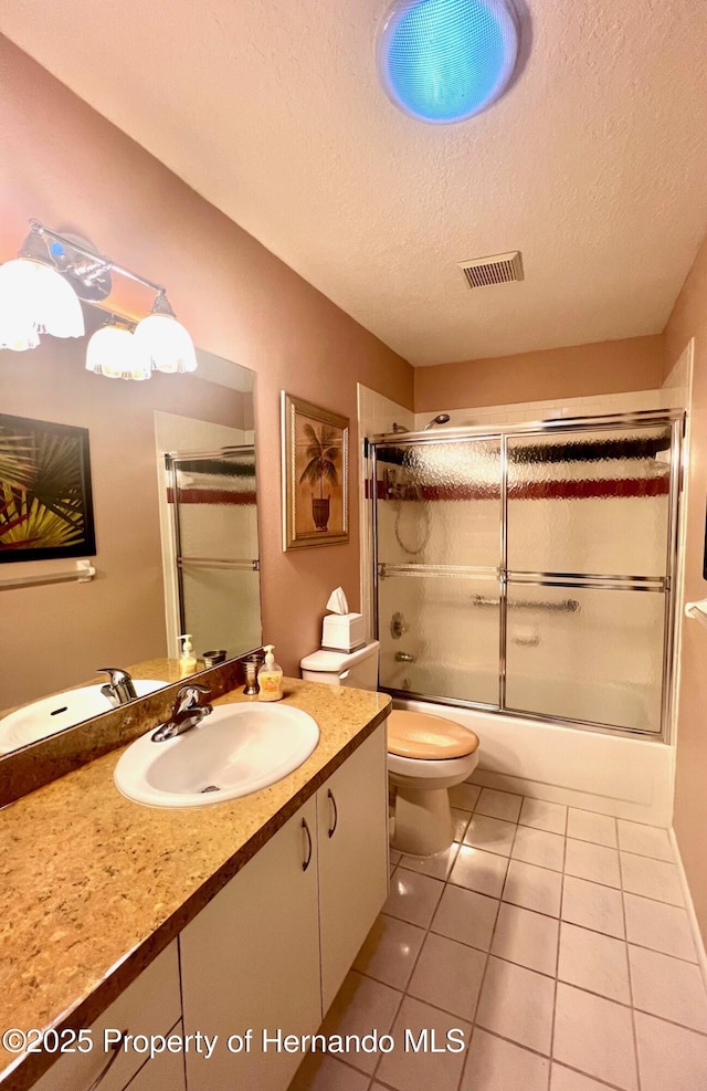 full bathroom featuring tile patterned floors, toilet, combined bath / shower with glass door, a textured ceiling, and vanity