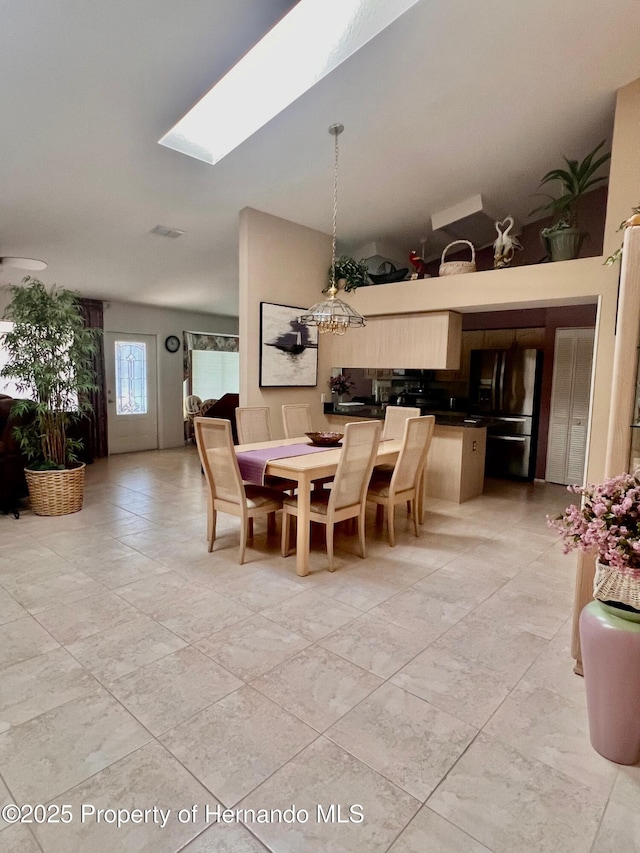 dining space with a skylight and high vaulted ceiling