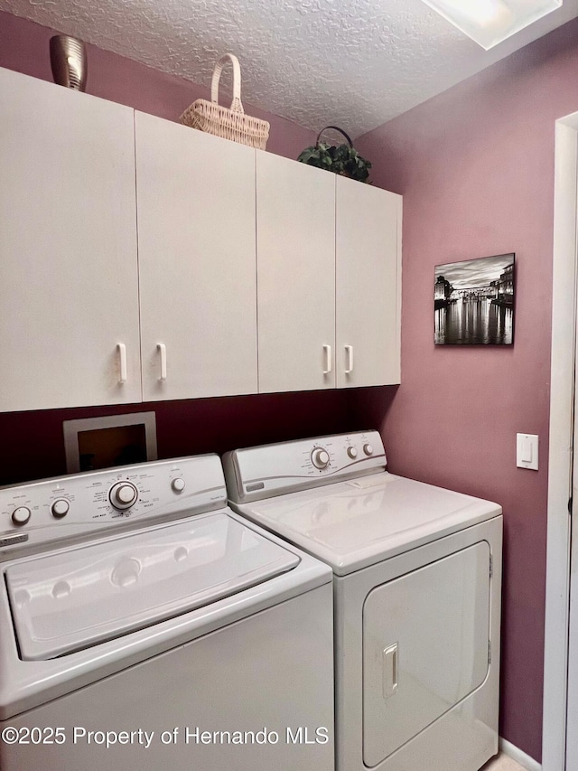 washroom featuring separate washer and dryer, cabinets, and a textured ceiling