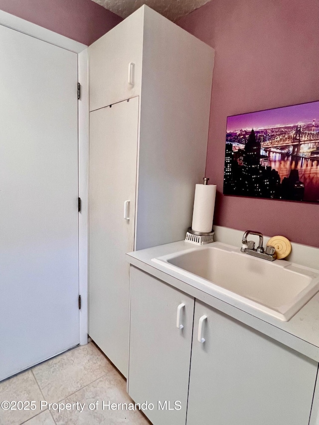 laundry room featuring sink and light tile patterned flooring