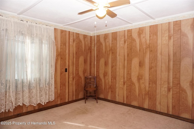 empty room with ceiling fan, wooden walls, and light colored carpet