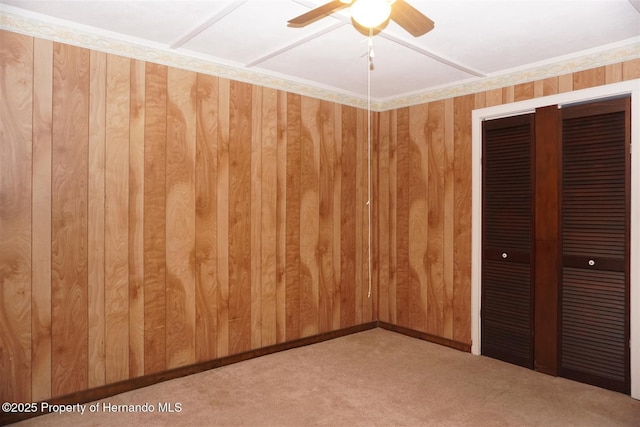 unfurnished bedroom featuring ceiling fan, a closet, and wood walls