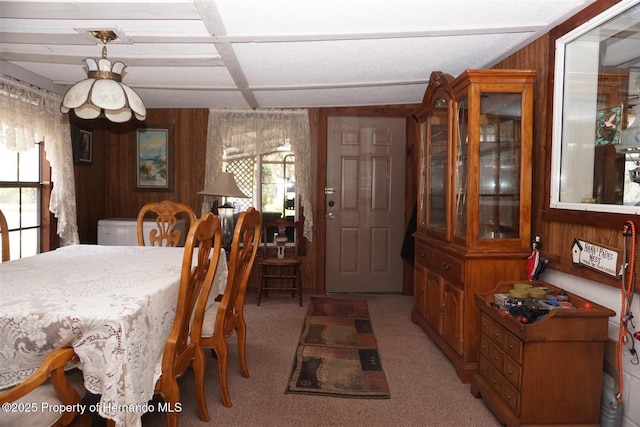 dining area featuring coffered ceiling, carpet flooring, and wooden walls