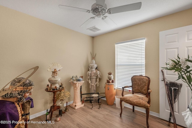 living area featuring ceiling fan and light hardwood / wood-style floors