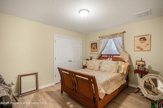 bedroom featuring a textured ceiling, light wood-type flooring, and a closet