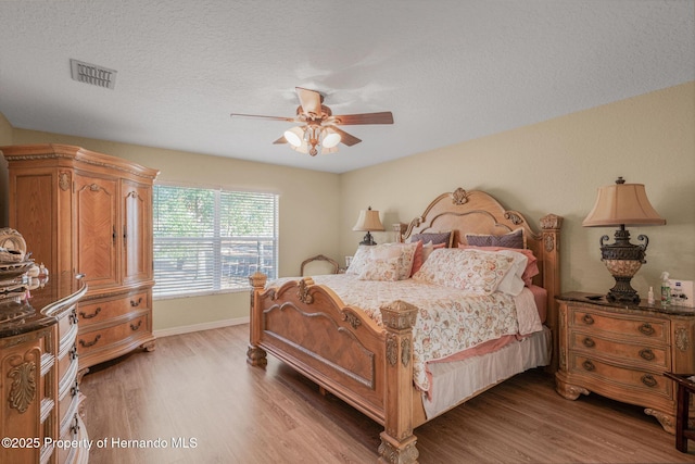 bedroom with hardwood / wood-style flooring, ceiling fan, and a textured ceiling