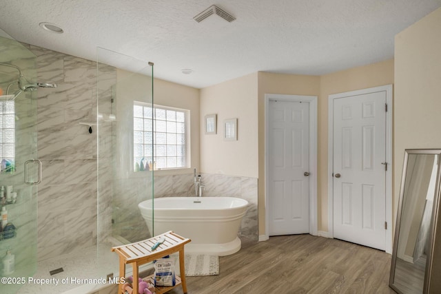 bathroom with hardwood / wood-style flooring, separate shower and tub, tile walls, and a textured ceiling