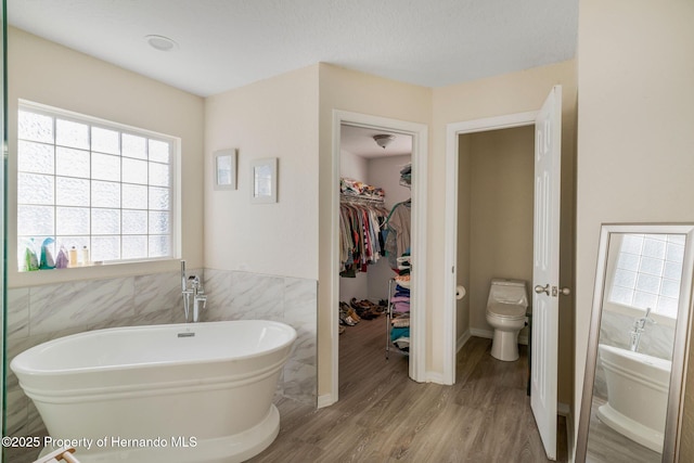 bathroom featuring hardwood / wood-style floors, a washtub, tile walls, and toilet