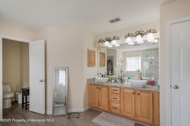 bathroom with vanity, wood-type flooring, toilet, and a tile shower