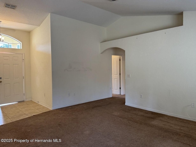 carpeted foyer entrance featuring an inviting chandelier and lofted ceiling