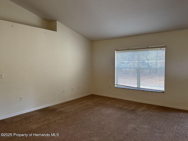 carpeted spare room featuring lofted ceiling