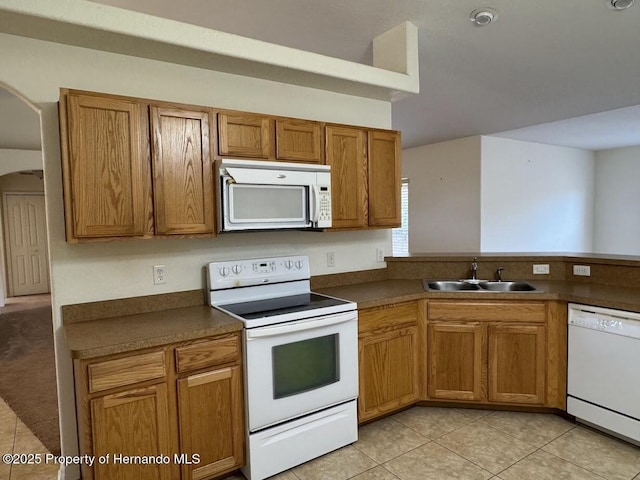 kitchen with light tile patterned flooring, white appliances, kitchen peninsula, and sink