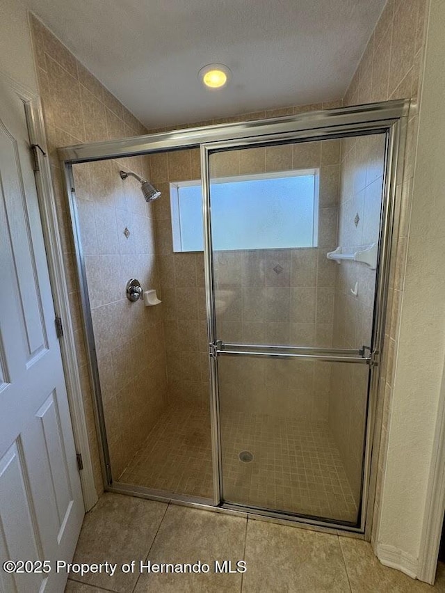 bathroom with a shower with shower door and tile patterned flooring