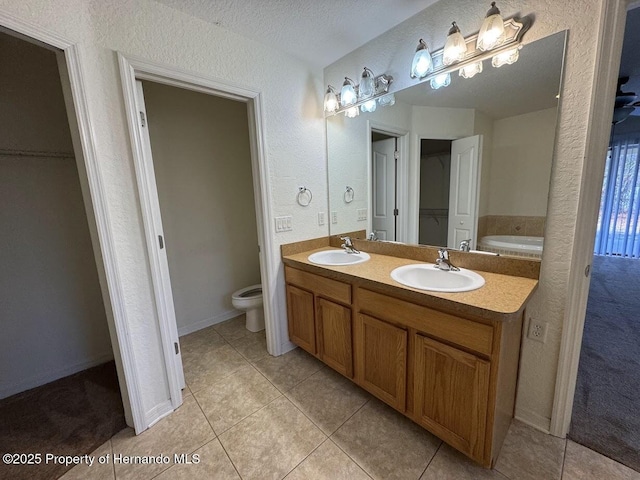 bathroom with toilet, a textured ceiling, vanity, a bathtub, and tile patterned flooring