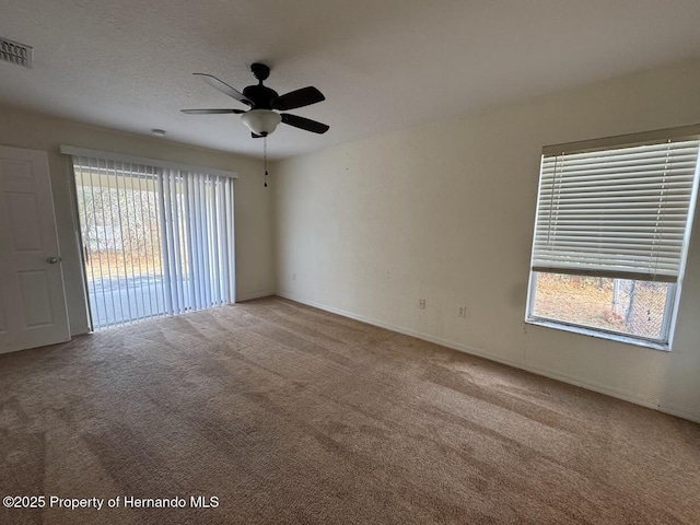 spare room featuring ceiling fan, a textured ceiling, a healthy amount of sunlight, and carpet flooring