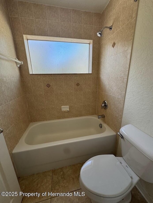 bathroom featuring tiled shower / bath and toilet