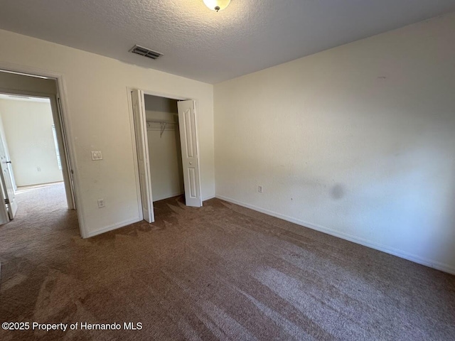 unfurnished bedroom with a closet, a textured ceiling, and carpet