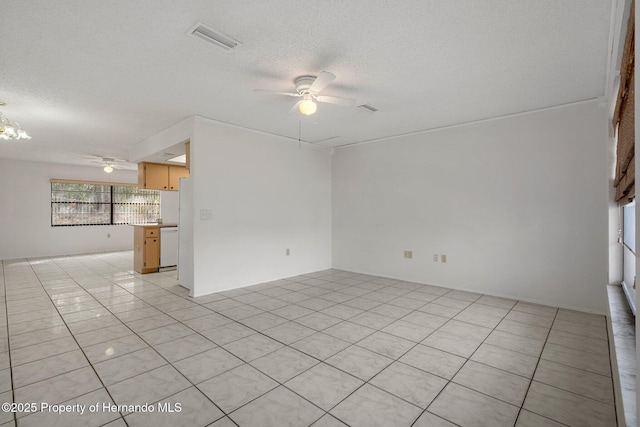 tiled empty room featuring ceiling fan with notable chandelier and a textured ceiling