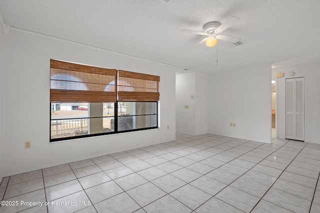 spare room featuring ceiling fan, light tile patterned floors, and a textured ceiling