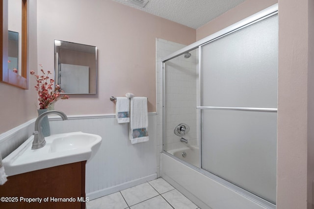 bathroom featuring tile patterned flooring, vanity, a textured ceiling, and shower / bath combination with glass door