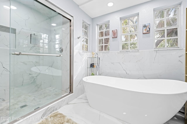 bathroom with a marble finish shower, tile walls, a freestanding tub, and marble finish floor
