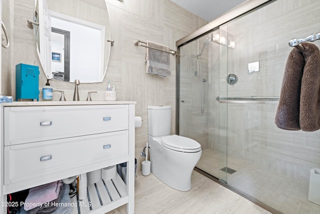 bathroom featuring wood finished floors, vanity, toilet, and a stall shower