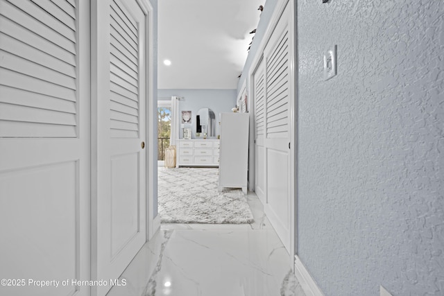 hallway with recessed lighting, marble finish floor, and baseboards