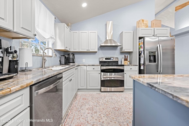 kitchen featuring light stone countertops, a sink, stainless steel appliances, vaulted ceiling, and wall chimney range hood