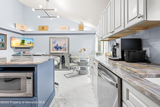 kitchen with lofted ceiling, white cabinetry, stainless steel appliances, light stone countertops, and marble finish floor