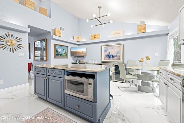 kitchen featuring an inviting chandelier, stainless steel microwave, vaulted ceiling, marble finish floor, and visible vents