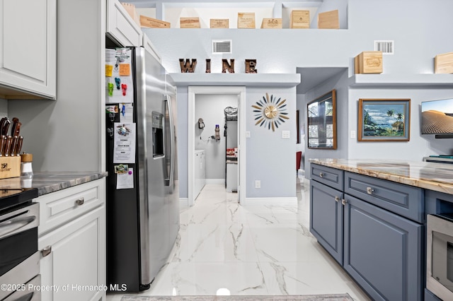 kitchen with appliances with stainless steel finishes, visible vents, washer and clothes dryer, and marble finish floor
