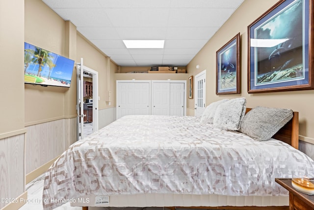 bedroom with wainscoting and a paneled ceiling