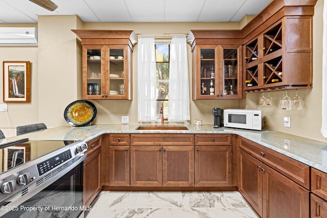 kitchen with light stone counters, a sink, stainless steel range with electric stovetop, white microwave, and marble finish floor