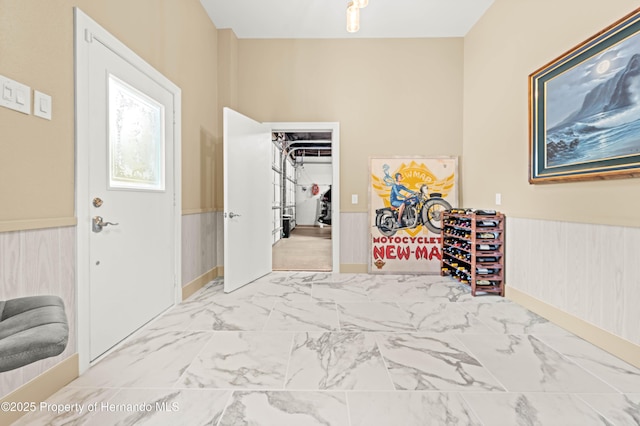 entrance foyer with a wainscoted wall and marble finish floor