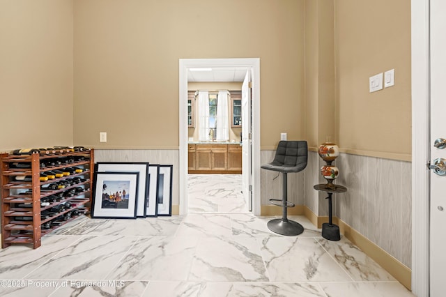 foyer entrance featuring a wainscoted wall and marble finish floor