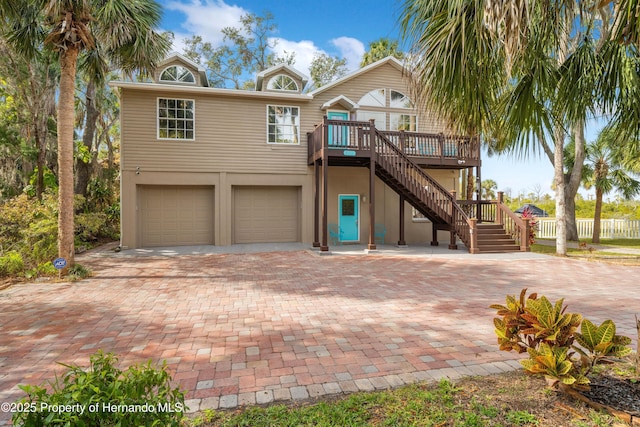 view of front of property featuring stairs, decorative driveway, an attached garage, and a wooden deck