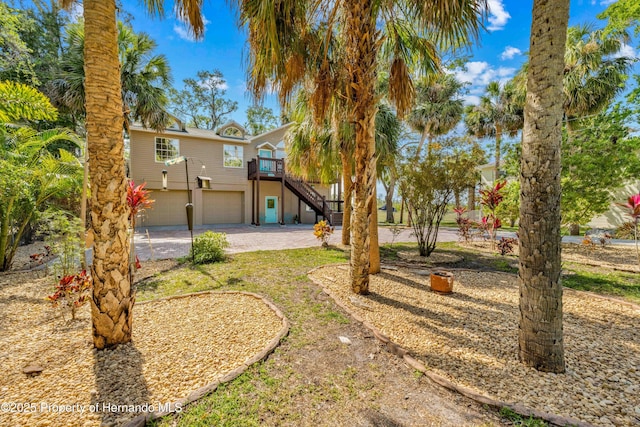 view of yard with a garage, driveway, and stairs