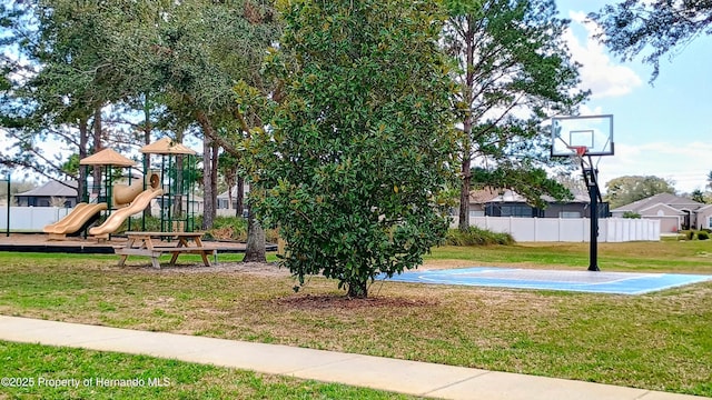 view of playground featuring basketball hoop and a lawn