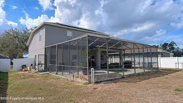 back of property with a patio, a swimming pool, and glass enclosure