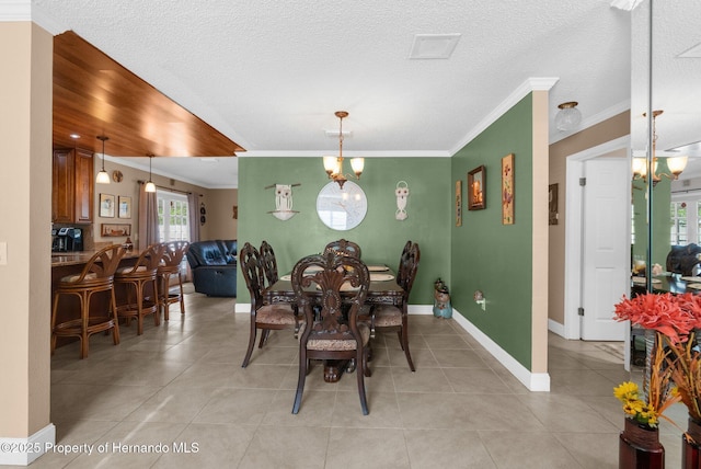 dining area featuring ornamental molding, light tile patterned floors, a notable chandelier, and a textured ceiling