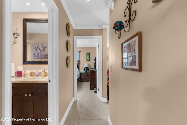 hall with ornamental molding, sink, a textured ceiling, and light tile patterned floors